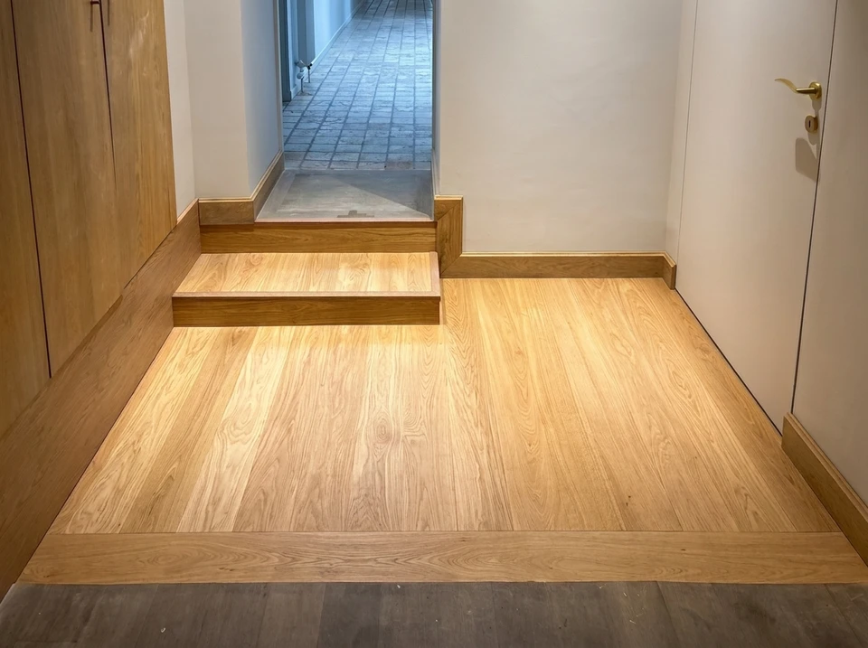 Salon moderne avec meuble TV suspendu blanc et bois, étagères murales intégrées, parquet en chêne massif