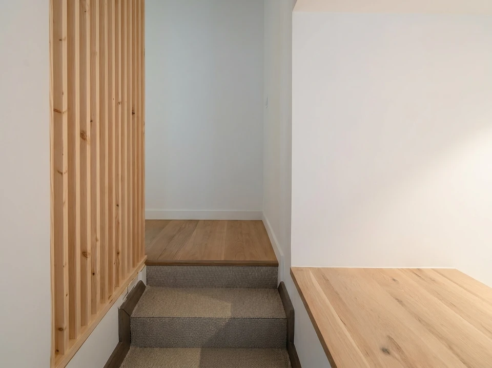 Intérieur moderne minimaliste avec escalier en bois, mobilier contemporain blanc et surfaces en bois clair